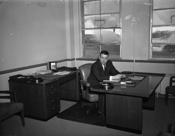 A man is smoking at a desk at the Wisconsin Alumni Research Foundation. 