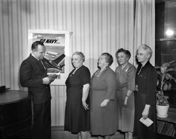 Chief Petty Officer Earl Woodward of the Madison navy recruiting office installing newly elected officers of the Navy Mothers' club. From the left are: Mrs. Margaret Atkins, commander; Mrs. Maude Schmidt, first vice-commander; Mrs. Avia MacLean, adjutant; and Mrs. Ida Owens, finance officer.