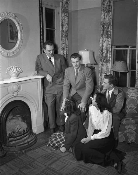 Pictured around the fireplace in the Lutheran Student Foundation, 228 Langdon Street, are counter-clockwise: the Reverend A. Henry Hetland, with University of Wisconsin students Paul Bockstrand, Kenneth Weig, Lois Woelffer, and Noreen Obercht.