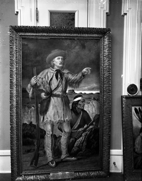 Portrait painting of Kit Carson, a famous trapper and guide of the west. The painting is leaning on a wall, with part of another painting on the right. Part of the T.B. Walker Indian Collection, on loan to the Wisconsin State Historical Society.