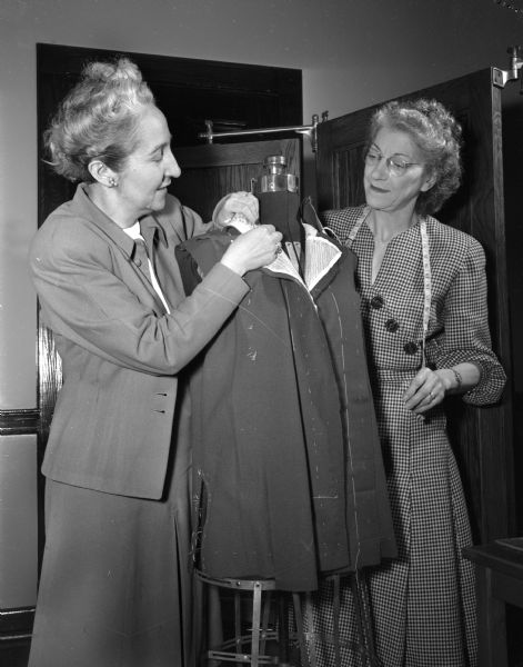 Helen Johnson, tailoring instructor, and Mrs. Edwin (Gertrude) Johnson, student, at Madison Vocational and Adult Education School, 211-213 North Carroll Street. Helen Johnson is working with fabric on a dress form, while Gertrude Johnson looks on with a tape measure around her neck.
