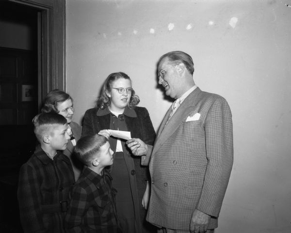 Roundy Coughlin, sports columnist for the <i>Wisconsin State Journal</i>, accepting a check from four children for his Fun Fund. Pictured left to right: Keith Sperling, Rochelle Dommershausen, David Dommershausen, Betty Sperling, and Roundy Coughlin.