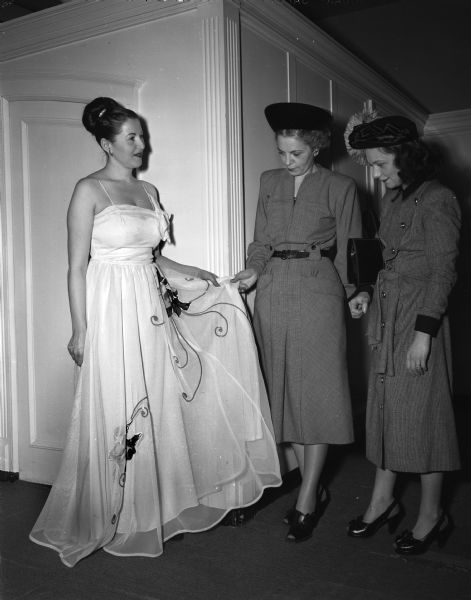 Mrs. J.J. (Helen) Sinagub is wearing the evening gown she will model at the style show of the National Council of Jewish Women. She is being admired by Mrs. Sol (Lucille) Martin and Mrs. Lee (Alma) Baron at Baron's tea room.