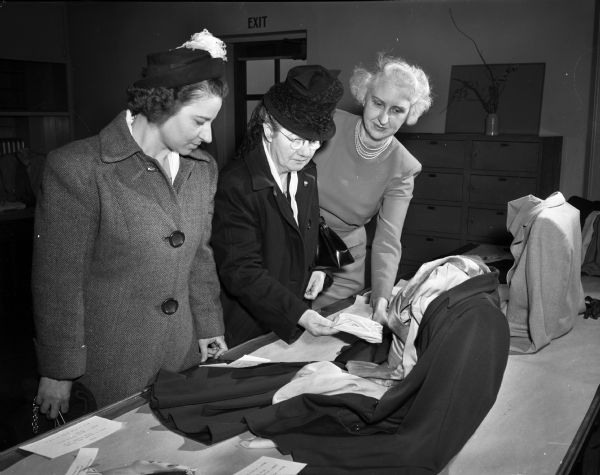 Three women looking at an exhibit at the University of Wisconsin Farm and Home Week showing color combinations for clothing and accessories. Pictured left to right are: Ava Martin, Prairie du Chien; Mrs. Fred Freeman, Gays Mills, and Cornelia Beckwith, Madison, University of Wisconsin Professor of Related Arts.