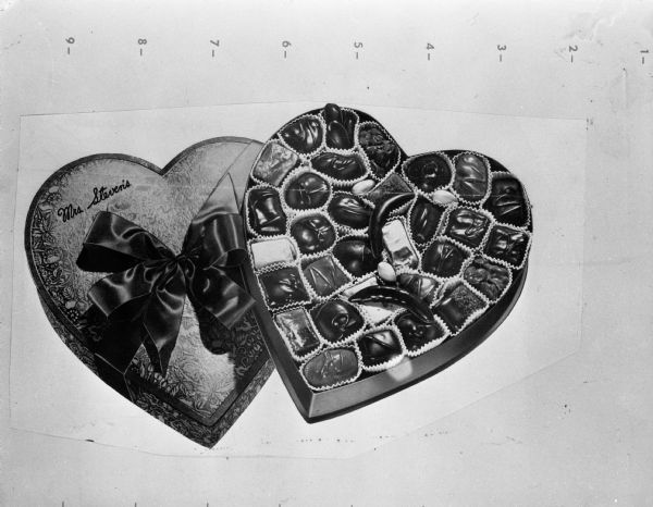 A close-up of a heart-shaped box of Mrs. Steven's candy with the cover removed and the candy on display. The illustration appears to be mounted on a board and there are numbers along the top.