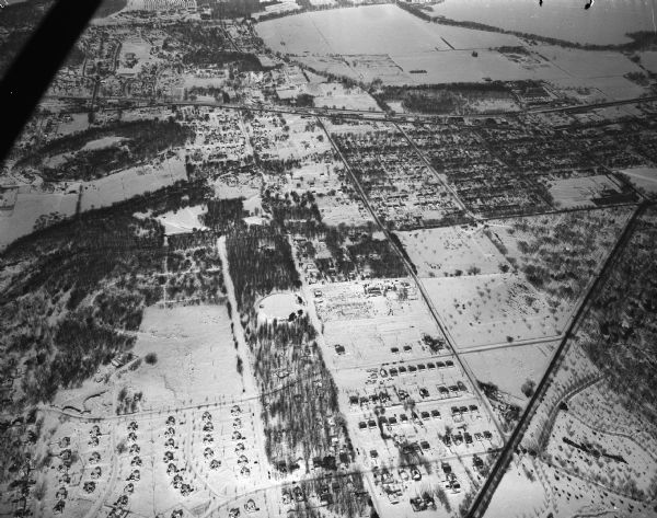 Looking north along Glenway Street. Visible are the reservoir, Hoyt and Quarry Parks, Resurrection and Forest Hill Cemeteries, Rentschler Greenhouses, Forest Products Laboratory, and Lake Mendota. The major streets are University Avenue, Regent Street, and Speedway Road. There is snow on the ground.