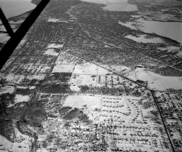 Looking east along Regent Street with snow on the ground. Visible are Lake Wingra, Monona Bay, railroad causeway across Monona, Lake Mendota, Hoyt Park, West High School, Camp Randall Stadium, Resurrection and Forest Hill Cemeteries, Glenway Golf course, and the reservoir on Glenway Street. Other major streets are Speedway Road, Mineral Point Road, and Monroe Street.