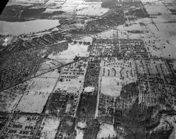 Aerial view of west side, looking south along Glenway Street. Visible are the reservoir, Lake Wingra, Forest Hill and Resurrection Cemetery, Hoyt Park. Major streets are Regent Street, Speedway Road, Mineral Point Road, Monroe Street, and Nakoma Road. There is snow on the ground.