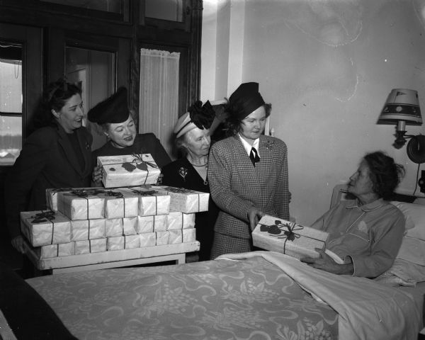 Madison Woman's Club members, left to right, Mrs. John C. Sammis, Mrs. George R. Holdhusen, Mrs. Leslie F. Van Hagan, and Mrs. Edward N. Hein are shown giving gifts to Mrs. W.J. Kiltz, a patient at Lake View Sanatorium.