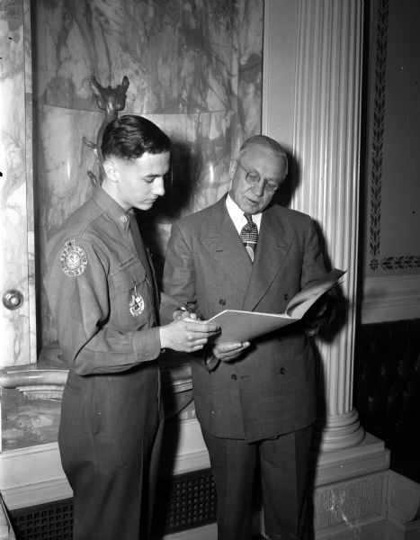 Governor Oscar Rennebohm accepting a report on the 1947 services of Wisconsin Boy Scouts from Steve Clark, Jr. (left) a member of Boy Scout Troop 1, Madison.
