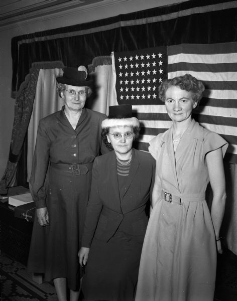 Pictured are three officers of the Dane County Rural Letter Carriers Auxiliary at their annual Washington's birthday meeting standing in front of the United States flag.