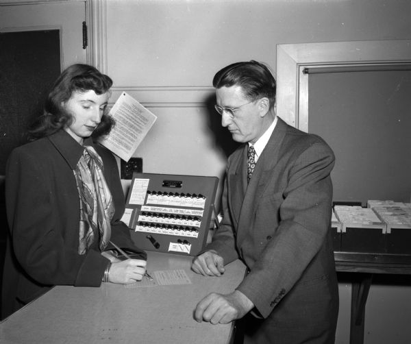 Mary Janet Hall, (at left) daughter of Mr. and Mrs. George Hall, registering at City Hall as a new voter, and City Clerk A.W. Bareis (at right.)
