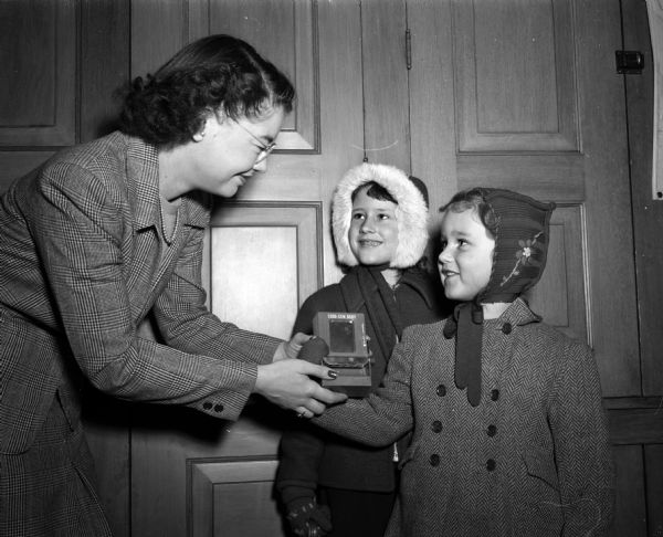 Sisters Suzanne and Jane LaCourt, daughters of Mr. and Mrs. H.A. LaCourt, donating their "choo-gum" savings of 79 cents to Dorothy Davis, head of the bookkeeping department at the <i>Wisconsin State Journal</i> for the "Annie's Friends" fund. The fund is for purchasing a new elephant for the Vilas Park Zoo (Henry Vilas Zoo)to replace Annie, who died Feb. 24, 1948.