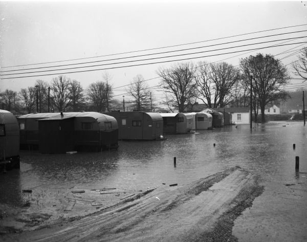 Flood at the University of Wisconsin-Madison East Hill Trailer Camp, located at 451 North Midvale Boulevard, south of University Avenue. Shown are several trailer homes surrounded by water.