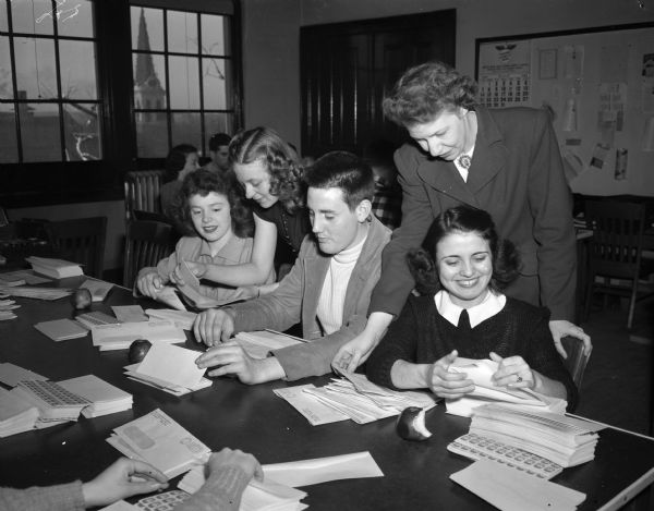 Vocational school students and Easter Seal Workers stuffing envelopes for the Easter Seal campaign for mailing to Madison residents. Pictured left to right are: Helen Spencer, student; Mrs. Dick (Doris) Harrison, campaign chairman; Doran Dieter, student; Mrs. Lela Josephson, campaign worker; and Helen Rache, student. Volunteers are being coordinated by the Junior Chamber of Commerce auxiliary (Jaycettes).