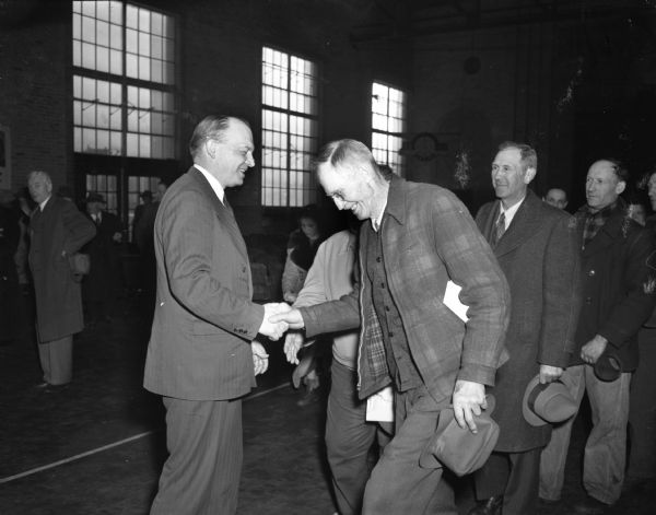 Harold E. Stassen (left), in Fort Atkinson, shaking hands with Ernest Marsh of Palmyra. Other men are lined up behind to shake hands.
