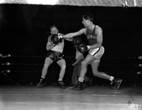 NCAA boxing tournament, University of Wisconsin, Bout 22, "Vito Parisi, Wisconsin, advanced to the NCAA semi-finals when he scoured an unanimous decision over Art Hughlett, Michigan State. The picture shows Parisi banging a hard right to Hughlett's chin in the third round.