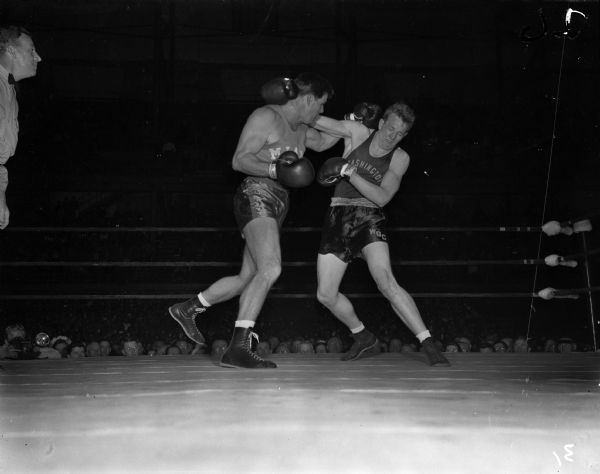 Washington State University boxer Bob Doormink, right, has just received a left hook from University of Miami boxer Art Saey, NCAA heavy weight defending champion who also won the title this year. The two men are participating in the NCAA championship being held at the University of Wisconsin-Madison Field House.