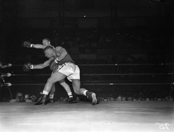 University of Wisconsin boxer Calvin Vernon, front, has just missed University of Virginia boxer Ralph Shoaf with a sweeping right while Shoaf has missed with a powerful left. The two men are participating in the light-heavyweight bout of the NCAA championship being held at the University of Wisconsin-Madison Field House.