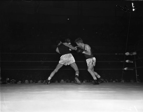 University of Wisconsin boxer James "Red" Sreenan, right, delivering a right punch to opponent Penn State boxer John Benglian. The two men are participating in a featherweight bout a the NCAA championship being held at the University of Wisconsin-Madison Field House. Sreenan won the bout and advanced to the featherweight championship bout.