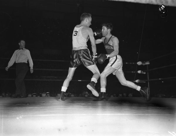 Wisconsin's Bob Apperson has just caught a left to the nose in the first round from Michigan State's Charles Davey in their lightweight bout. The two men are participating in the NCAA championship being held at the University of Wisconsin-Madison Field House.
