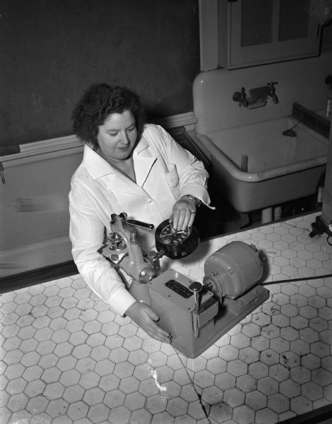 Margaret Cooper, Associate Professor of Home Economics at the University of Wisconsin, Madison and director of the textile laboratory, testing the bursting strength of a textile sample.