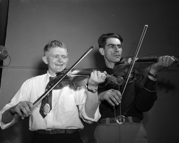 Posed with their fiddles are Theodore Rygh, Jr., of Woodford, left - third place finisher, and Herman "Tex" Falkenstein, of Madison, right - second place finisher at the Old-Time Fiddlers' contest at the Madison Community Center.