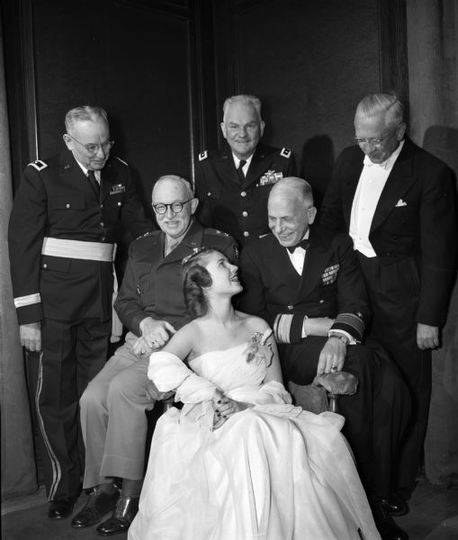 University of Wisconsin 1948 Military Ball Queen, Mary Schneiders of San Diego, California, pictured with some of the dignitaries who attended the dance at the Memorial Union. From left are Adjt. Gen. John F. Mullen; Maj. Gen. John P. Lucas, deputy commander of the Fifth Army area; Maj. Gen. P.I. Williams, commanding general of the Second Air Force; Rear Admiral J. Cary Jones, commandant of the Ninth Naval District; and Governor Oscar Rennebohm.