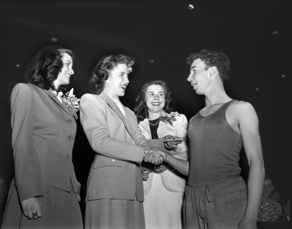 Charles Starr, Richland Center, winner of the 60-yard low hurdles, is being given his award by Queen Mary Lou Sorenson, while Gloria Sutcliffe and Nancy Lange look on. The Madison West High School Relay Carnival was held at the Field House.
