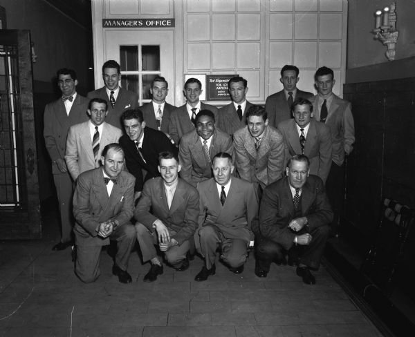 Group portrait of the Wisconsin boxing team that won the national championship this year. Shown back row, left to right: Vito Parisi, Madison, heavy-weight, 1948 NCAA champion; Darrell Burmeister, Janesville, heavy-weight, 1947 NCAA semi-finalist; Glen Nording (?), Madison, who has boxed at 155, 165 and 175 during his career at Wisconsin; Paul Kotrodimos, Milwaukee, 130-pounder; Robert Apperson, Long Beach, California, lightweight 1947 NCAA runner-up; Dwaine Dickinson, Tomah, 145-pounder and James Sreeran, Beloit, 130-pounder, 1948 NCAA runner-up.  Middle row, left to right: Don Dickinson, Tomah, welterweight NCAA runner-up 1947 and champion in 1948; John Lendenski, Natrona, Pennsylvania, middleweight, 1947 NCAA champion and semi-finalist in 1948; Calvin Vernon, Milwaukee, lightheavyweight, 1948 NCAA champion; Bob Brigham, Madison, 130-pounder; Steve Gremban, Goodman, bantamweight, 1947 NCAA runner-up and champion in 1948. Bottom row, left to right: John J. Walsh, Wisconsin varsity coach; Ray Hoague, Janesville, varsity manager; Jack Ferguson, Madison fan who annually gives the George Downer Memorial Trophy and Vernon Woodward, Wisconsin assistant coach.