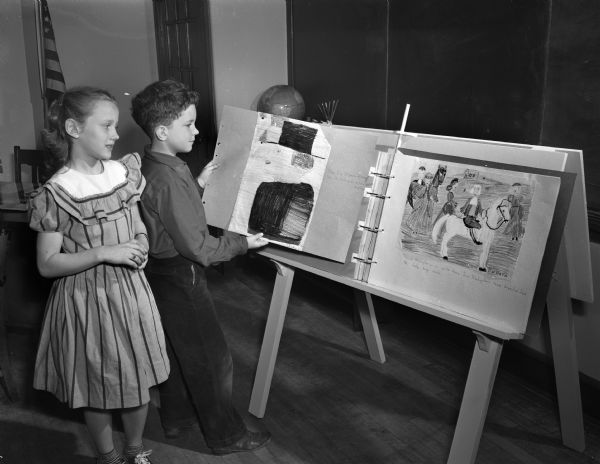 Two Randall School students admiring a picture of a Pilgrim and another of George Washington made by Randall school third graders and displayed on an easel. Pictured are Susan McBeath and Steve Ela.