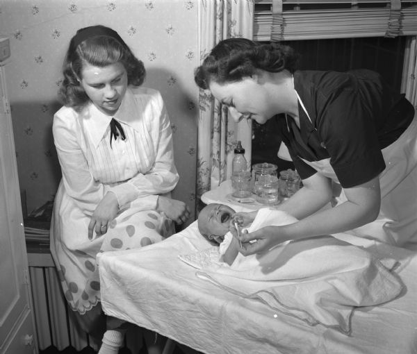 Visiting nurse Maude Rydberg of the Madison Visiting Nurse Service, shows Mrs. William E. Johnson, the former Jane Weston, the proper way to use the cotton applicator.