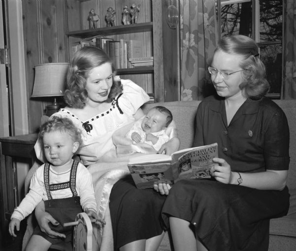 Visiting nurse Esther Sorensen of the Madison Visiting Nurse Service is advising Mrs. Chester B. Van Roo, the former Mary Lou Bell, on the care of her children, Chester, Jr., 18 months, and Mary Elizabeth, 2 months.