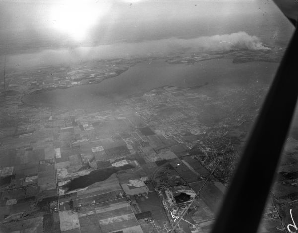 Aerial photograph of two brush fires on the north side of Lake Mendota. Taken over the west side of Madison looking northwest across Lake Mendota.