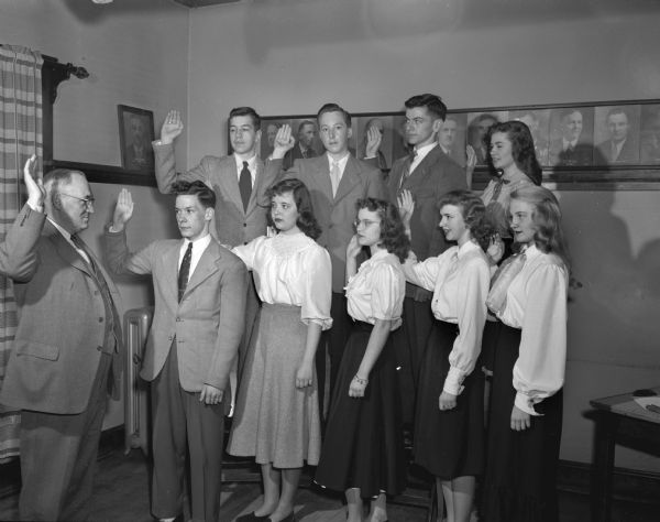 Nine members of the Madison East Side Youth Activities Council taking the oath of office being administered by Dane County Judge Fred M. Evans at the East Side Business Men's clubhouse.