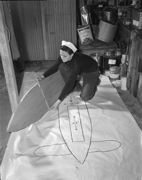 Frank Meyers measuring the floorboard of his 1948 Soap Box Derby racer to see that it compares exactly with the full-scale plans he drew before starting to build the car.