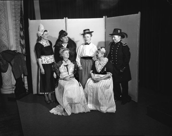 Group portrait of members of the Madison Woman's Club wearing costumes depicting characters in works of literature by Wisconsin authors. Pictured seated left to right: Mrs. Earl (Jessie) Rothe and Mrs. Herman (Fannie) Mack. Standing left to right: Mrs. C.B. (Lydia) Langenstein, Mrs. John E. (Frances) Dudley, Mrs. Vernon A. (Lorraine) Rucker and Mrs. Arthur L. (Celia) Tatum.