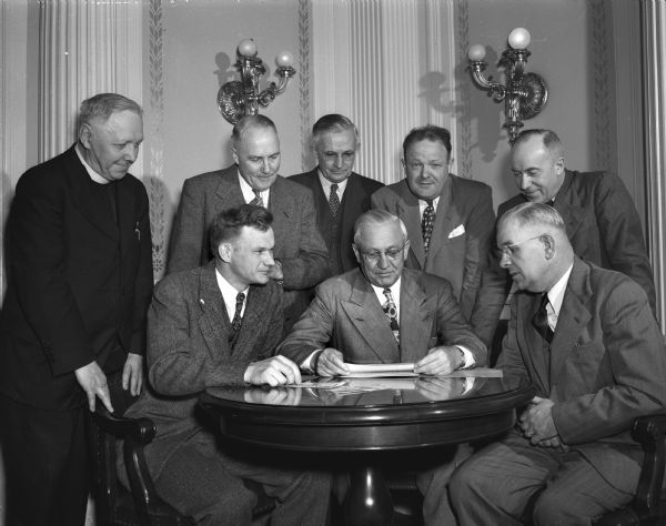 Governor Oscar Rennebohm met with executive committee members of Christian Rural Overseas Program (CROP), to endorse the relief food program the organization is sponsoring. Seated left to right: Robert Lewis, Madison, editor, REA News and state director of CROP; Governor Rennebohm and the Rev. M.A. Sorenson, McFarland Lutheran Church, chairman of the CROP executive committee. Standing left to right: The Rev. Hasusler, Sacred Heart's church, Sun Prairie; Professor W.W. Clark, Madison, associate director, University of Wisconsin College of Agriculture extension division; Wilbert Witte, Madison state department of agriculture; Ellis H. Dana, Madison, executive secretary, Wisconsin Council of Churches; and the Rev. William C.F. Hayes, Madison, Wisconsin Council of Churches.