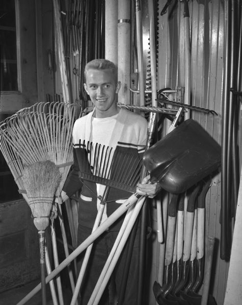 La Verne Haak, chairman of the Madison Youth Council's second annual spring clean-up campaign, is shown with equipment to be used for the project. His tools include several shovels, rakes and a broom. Haak, a West High school senior, is the son of Mr. and Mrs. Harold J. Haak, 213 S. Park Street.