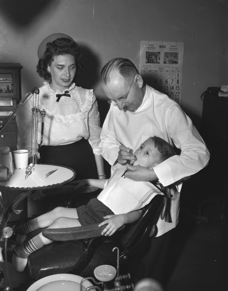 Mrs. Zean (Gladys) Braiger observes a dentist checking the teeth of Ronald Opelt. The mothers of Madison's Parent-Teacher associations promoted a "summer round-up" for all pre-school children in the city, promoting a thorough physical and dental check-up before entering school in the fall.