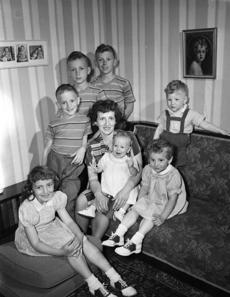 A Mother's Day family portrait of Mrs. George T. (Beatrice) Fox, 2310 Rugby Row, and her seven children. Seated at the left is Terry, 8. Standing behind her are brothers Timothy, 7, Nat, 10 and Tom, 11. Seated in her mother's lap is Patricia, 10 months, and Roberta, 3 sits at her right. Micheal, 2, stands behind Roberta. Mrs. Fox is the wife of University of Wisconsin football end coach.