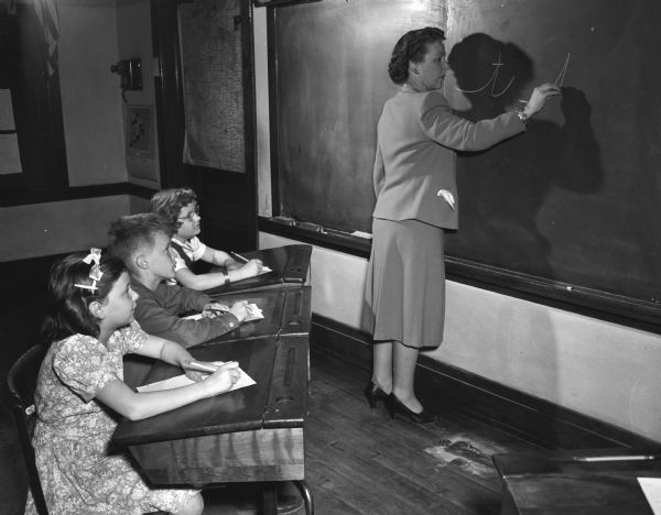 Teacher Mary Kier, fourth grade teacher at Nakoma Elementary School, 3870 Nakoma Road, stands at the blackboard demonstrating a handwriting technique to her students.