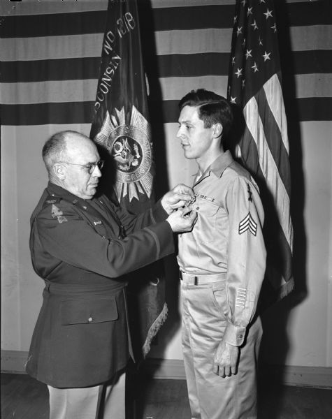 Colonel George Sherman, chief of staff of the 32nd division National Guard is shown decorating Sargeant Harold L. Endres with medals. Endres was a World War II veteran, and was wounded in action in 1945. The ceremony was at the Veterans of Foreign War clubhouse.