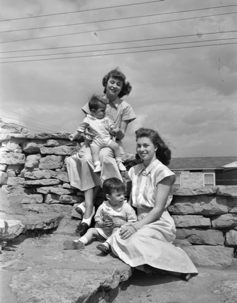 Seated outdoors on a stone wall are Mrs. Kendall A. (Mary) Niglis, 3805 Hammersley Avenue, and her two sons, Kendall Junior, two-years old, and John Kreigh, 11 months, and her sister, Louisa Cushwa, Williamsport, Maryland.