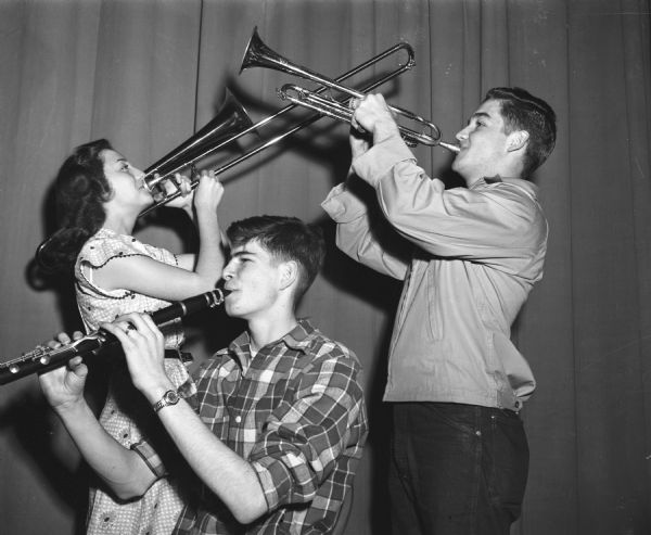 Central high school musicians pose while rehearsing for a city wide concert by the bands, orchestras and choruses of East, West, Central and Wisconsin high schools held at the University of Wisconsin-Madison Stock Pavilion. Left to right: Jo Raimond, trombonist; David Marsh, clarinetist; and Doster "Doc" DeHaven, cornetist.