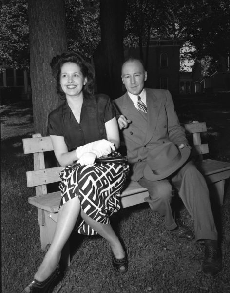 Louis Dousman, great grandson of Hercules Louis Dousman who built the home, is seated on a bench on the lawn with his wife.
