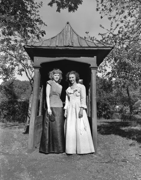 Eudora Kolowinski, from Prairie du Chien, Miss Crawford County, and Bevery Johnston, Ferryville, Miss Villa Louis, in formal dress, stand in front of the pergola. They are queens of the four-day celebration.