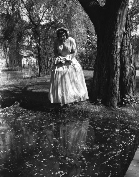 Mrs. W.H. Guest, Madison, dressed in costume, uses the petal strewn pool for a mirror.