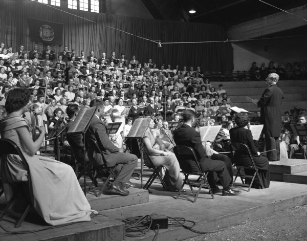 Dr. Sigfrid Prager conducting the Madison Civic Symphony Orchestra, the Madison Civic Chorus, the University of Wisconsin chorus and soloists in his farewell concert, held at the University of Wisconsin-Madison Stock Pavilion. Dr. Prager was the conductor of the civic groups for twenty-one years.