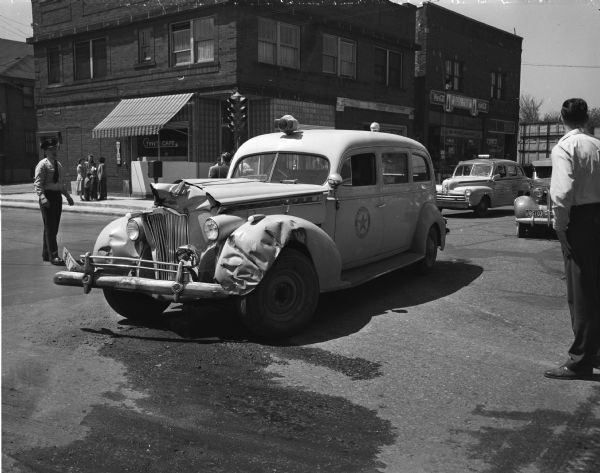 A police ambulance, speeding a 3-year old, David King, seriously injured accident victim to a hospital, crashed into a Padgham Painting Co. truck, driven by Elmer C. Evans, that turned into its path at Park and Regent Streets. Also shown in the photograph: Tiny's Cafe, 901 Regent Street, and Fumusa's Grocery, 907 Regent Street in the Greenbush neighborhood.